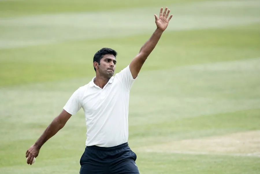 A cricket fast bowler with the arm loaded high overhead
